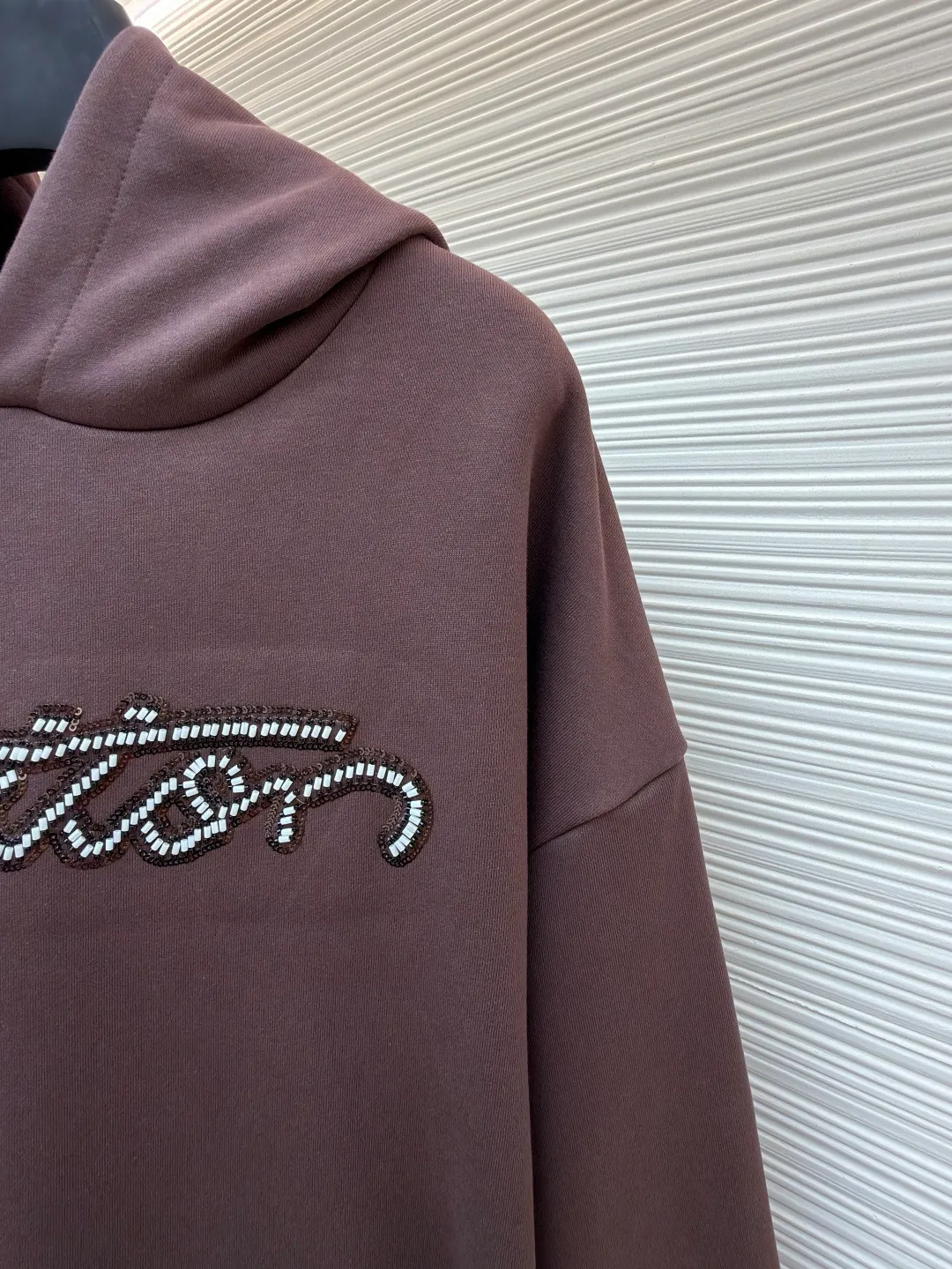 LOUIS VUITTON beaded embroidered letter hooded sweatshirt ●Item number: 1682118-A60 ●Material: pure cotton fish scale base fabric ●Technology: Pearl embroidery production ●Color: brown ●Version: fitted version ●Weight: about 830 grams ●Size: S-M-L-XL ●Description: The fabric is made of 26S double yarn + 10S fish scale bottom brushed fabric, weight 380g, with 21S double yarn 2*2 rib, weight 380g. This kind of fabric is treated with fleece to form a layer of soft and plump fluff on the inside; the improved fish scale knitting method forms a delicate concave and convex texture on the bottom surface, similar to the arrangement of fish scales. Effectively increases the air storage layer and improves thermal insulation performance. The front of the fabric is smooth and smooth, while the back is soft and waxy. It has excellent moisture absorption, breathability, wrinkle resistance and drape, and is thicker and crisper than ordinary sweatshirt materials. It gives clothes excellent warmth retention, breathability and skin-friendly touch. The Vuitton script on the chest is embroidered with beads. During the embroidery process, tiny beads are fixed on the fabric together with embroidery thread. The direct characteristics brought by this process are a strong three-dimensional sense, a unique sense of weight and a reflective effect that changes with the light. The overall wiring is straight and delicate, the fabric is comfortable and soft, and the color is consistent without color difference. It can be matched with the same style to create a fashionable look and control various occasions. Customized accessories, complete with three standards, same style for men and women!